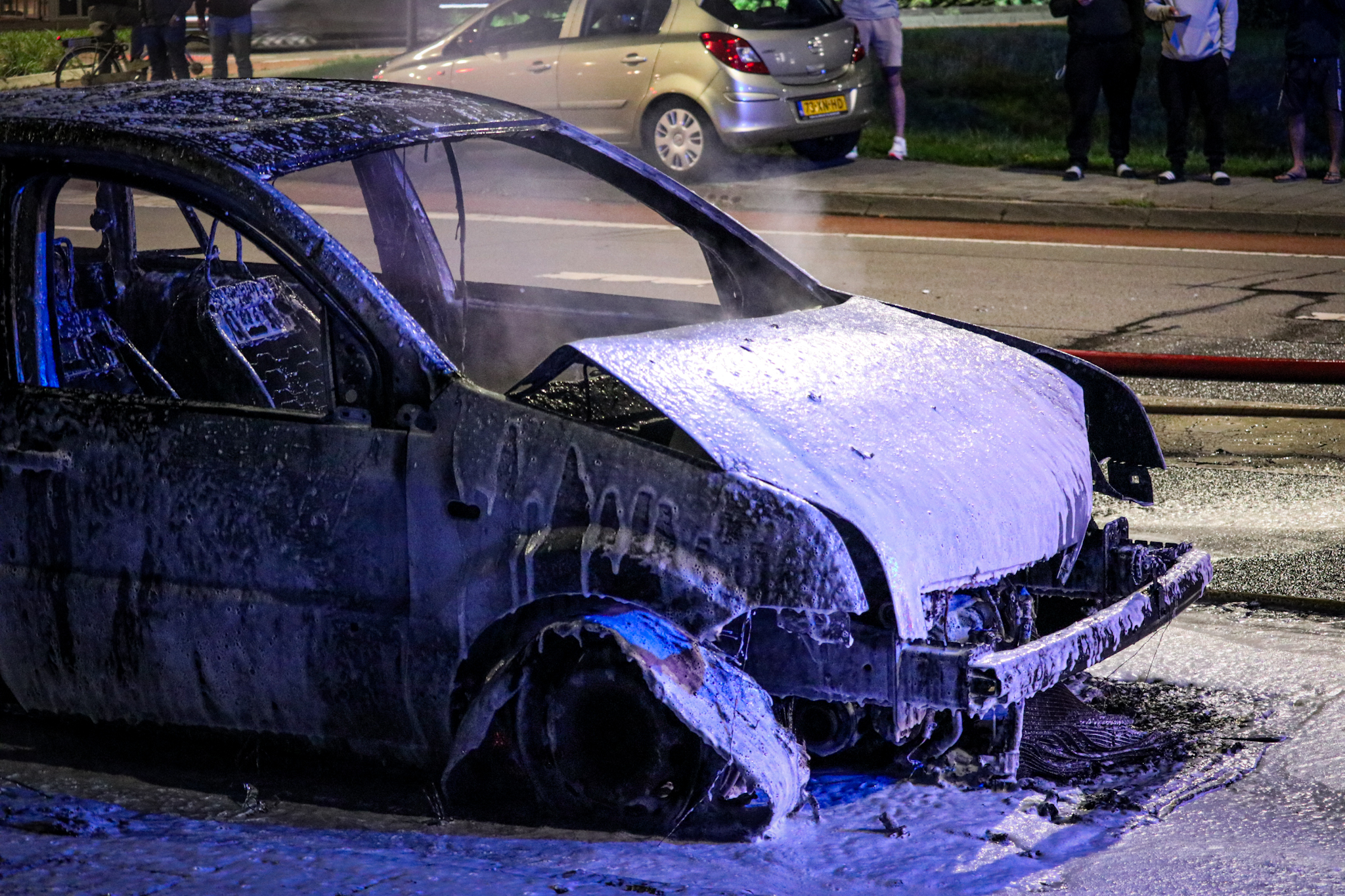 Rijdende auto vliegt in brand, brandweer zet water en schuim in - foto